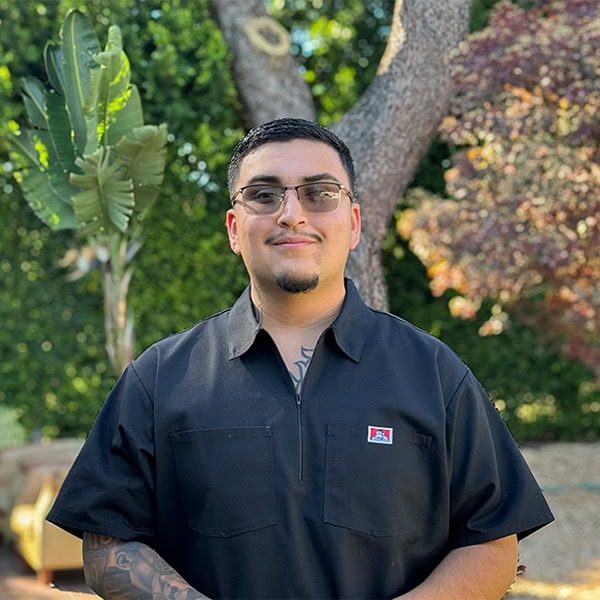 San Fernando Rescue Mission volunteer in black shirt outdoors with trees in background.
